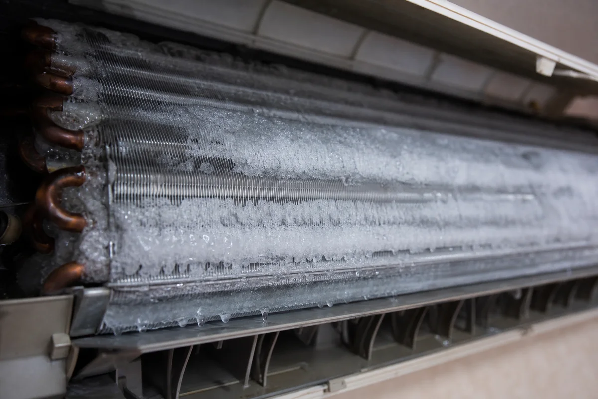 Ice covering the evaporator coil inside an open wall-mounted aircon